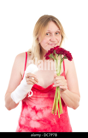 Frau mit bandagierte Hand schnuppert an Blumen Stockfoto