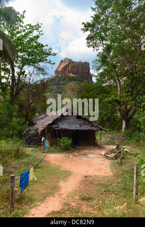 Hütte vor hohen Felsen unter grünen Wald. Sigiriya, Lion es Rock mit alten Felsenburg Festung. Sri Lanka Stockfoto