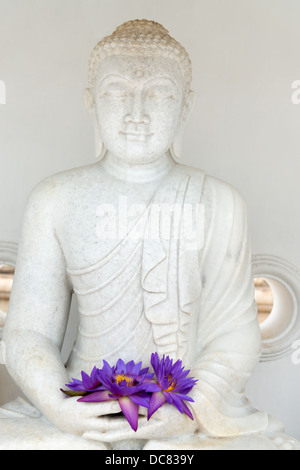 Bild Buddhastatue mit frischen Rauchfang Sterne Seerose oder Sterne Lotusblüten in Händen Stockfoto