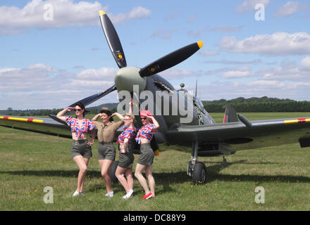 Maidenhead, Berkshire, England, UK. 11. August 2013.  Retro-Festival in White Waltham Flugplatz. 1940er Jahren bekleideten Frauen posieren von Supermarine Spitfire. Bildnachweis: Mark Beton/Festivals/Alamy Live-Nachrichten Stockfoto