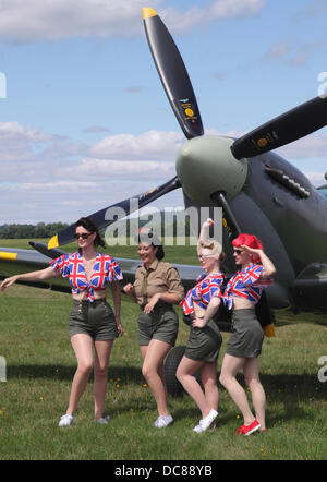 Maidenhead, Berkshire, England, UK. 11. August 2013.  Retro-Festival in White Waltham Flugplatz. 1940er Jahren bekleideten Frauen posieren von Supermarine Spitfire. Bildnachweis: Mark Beton/Festivals/Alamy Live-Nachrichten Stockfoto