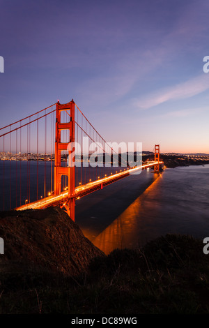 Verlieren - bis auf die Golden Gate Bridge, die orange Lichter im Wasser und beleuchtete Skyline der Stadt in der Dämmerung Stockfoto