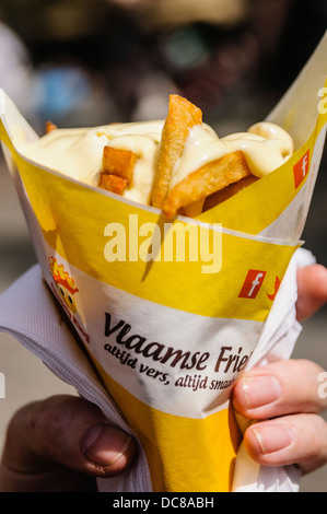 Eine Person hält einen Kegel von Pommes (Chips) mit Mayonnaise aus einem niederländischen Fast-Food-Kette in Amsterdam in den Niederlanden Stockfoto