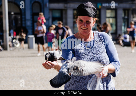 Tauben, die Landung auf die Hand einer Frau in Amsterdam Stockfoto