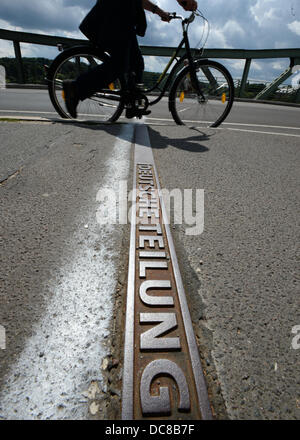 Ein Radfahrer führt ein Metallstreifen, die ehemalige innerdeutschen Grenze auf der Glienicker Brücke in Potsdam, Deutschland, 31. Juli 2013 markiert. Morgen war (13. August 2013) vor 52 Jahren die Berliner Mauer gebaut. Die 155 km lange Mauer in zwei Hälften Berlin geschnitten und versiegelt die Teilung Deutschlands in die BRD und die DDR die bis 9. November 1989 dauerte. Foto: RALF HIRSCHBERGER Stockfoto