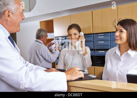 Beschäftigt Empfang in einem Krankenhaus mit Ärzten und Personal an der Rezeption Stockfoto
