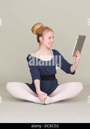 Junge blonde weibliche Teenager im Ballett Kleid mit einem TabletPC Stockfoto