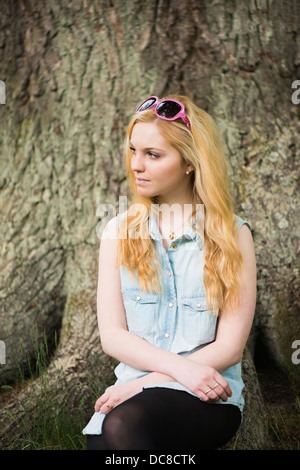 Eine junge blonde, attraktive Frau vor Baum in einem park Stockfoto