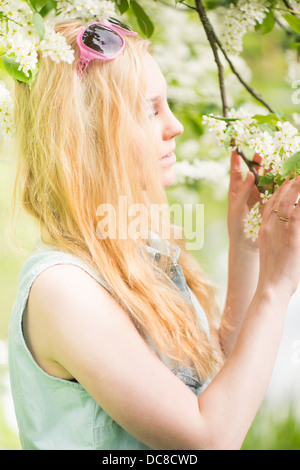 Natur-Szene mit einer jungen attraktiven Frau von einem Baum in Blüte Stockfoto