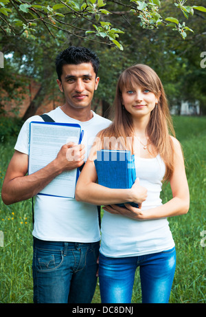 Zwei Studenten-Mann und ein Mädchen studieren in Park mit Buch im freien Stockfoto