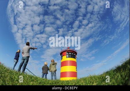 Eine Familie steht neben dem Leuchtturm Pilsum in Ostfriesland in der Nähe von Pilsum, Deutschland, 10. Juni 2013. Der Leuchtturm von 1891 bis 1915 in Betrieb war und ist ein Wahrzeichen von Ostfriesland. Foto: JULIAN STRATENSCHULTE Stockfoto