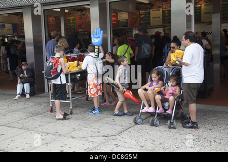 Familie isst Mittagessen auf dem Bürgersteig im Original Nathans berühmt für seine Hot Dogs auf Coney Island. Stockfoto