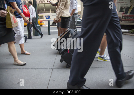 Fußgänger mit den Füßen auf dem Bürgersteig entlang der 42nd Street zwischen der 5th und Madison Avenue in New York City. Stockfoto