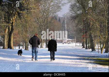 Wanderer im Windsor Great Park im Schnee mit Totempfahl in der Ferne Hund Stockfoto
