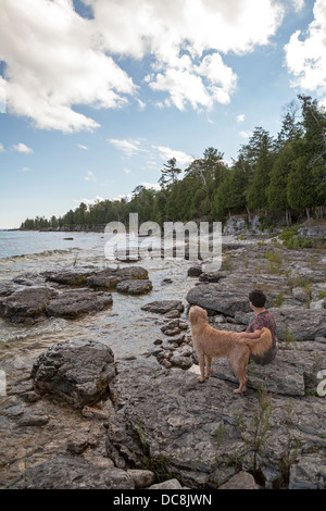 Eine Frau und ihr Hund teilen einen ruhigen Moment vom Lake Michigan auf Washington Island, Wisconsin. Stockfoto