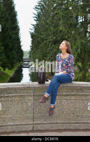 Gruppentour Mädchen sitzt auf einer alten Steinbrücke in den Nadelwald Stockfoto