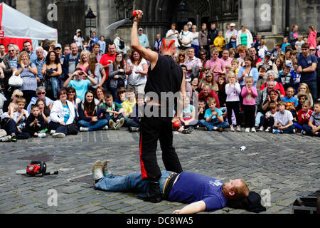 West Parliament Square, Edinburgh City Centre, Schottland, Großbritannien, Montag, 12. August 2013. Street Performer Mighty Gareth bereitet sich darauf vor, während des Edinburgh International Festival Fringe ein Messer und Bälle über einem Freiwilligen aus dem Publikum zu jonglieren Stockfoto