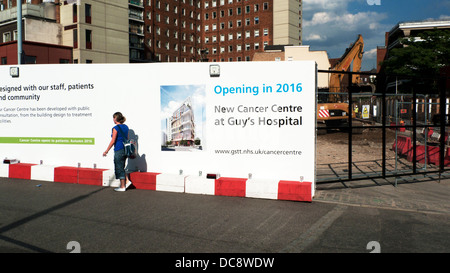 Eine Frau zu Fuß vorbei an Schild auf Horten Ankündigung 2016-Eröffnung des neuen Krebs-Zentrums am Guy's Hospital in Southwark, London UK Stockfoto