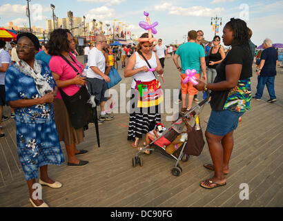 Brooklyn, New York, USA. 10. August 2013.  Auf Coney Island Boardwalk trägt IVELIZ BALTAZAR, von Harrison, New Jersey, eine bunte Ballon Mütze und Schürze, wie sie für ein Kleinkind Mädchen Ballon Formen kreiert. Stockfoto
