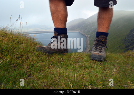 Mann trägt alte Stiefel & Shorts über Marchlyn Mawr Reservoir von Bwich y Marchlyn knapp unter den Gipfel Elidir Fawr gesehen Stockfoto