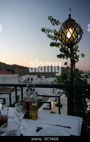 Blick über Lindos, Rhodos, Griechenland, vom Restaurant auf der Dachterrasse bei Sonnenuntergang, in der Nähe unter der Festung und die Akropolis von Lindos. Stockfoto