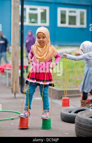 Der St.-Pauls-Kindergarten und das Kinderhaus, Bristol UK - A somalische Mädchen auf Stelzen auf dem Spielplatz spielen. Stockfoto