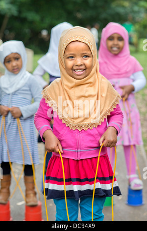 Der St.-Pauls-Kindergarten und das Kinderhaus, Bristol UK - A somalische Mädchen auf Stelzen auf dem Spielplatz spielen. Stockfoto