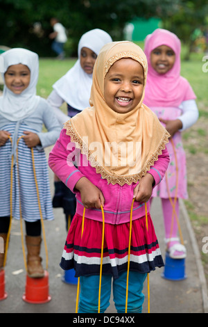 Der St.-Pauls-Kindergarten und das Kinderhaus, Bristol UK - A somalische Mädchen auf Stelzen auf dem Spielplatz spielen. Stockfoto