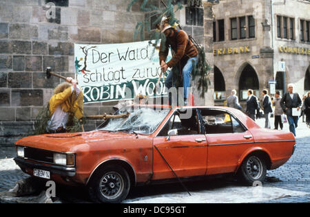 Mitglieder der Umweltorganisation Robin Wood als Bäume verkleidet sind und schlagen ein altes Auto als eine Protestaktion gegen das Waldsterben, fotografiert am 9. November 1989. Stockfoto