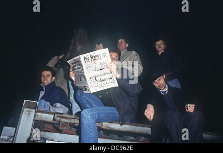 Ein Mann liest Boulevardzeitung "B.Z." sitzt an der Berliner Mauer als die Grenze in Ost-Berlin, DDR, 10. November 1989 geöffnet ist. Stockfoto