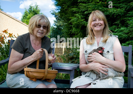 Frau mit Bluebell Huhn saß Mutter halten frisch gesammelten Eier im Korb, aufgenommen im Garten in Bristol, Großbritannien Stockfoto