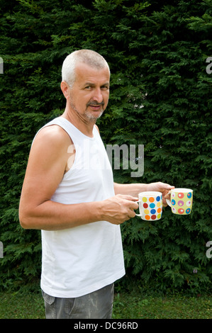 Kaukasischen Mann mit Tassen Tee im Garten, genommen in Bristol, Großbritannien Stockfoto