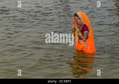 Frau trägt einen orangefarbenen Sari in Baden in der Sangam, dem Zusammenfluss der Flüsse Ganges und Yamuna Saraswati, die Stockfoto