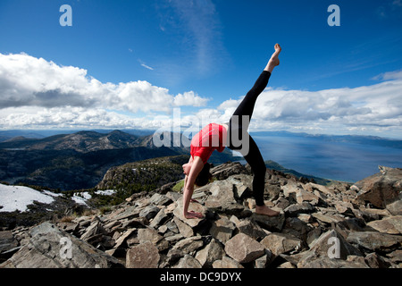 Eine Frau führt Yoga auf Mount Tallac mit Blick auf Lake Tahoe an einem schönen Nachmittag in der Nähe von South Lake Tahoe, CA. Stockfoto