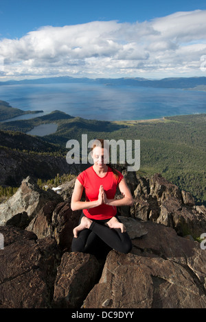 Eine Frau führt Yoga auf Mount Tallac mit Blick auf Lake Tahoe an einem schönen Nachmittag in der Nähe von South Lake Tahoe, CA. Stockfoto