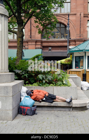 Obdachloser schlafen auf einer konkreten Bank in der Innenstadt von Montreal. Stockfoto