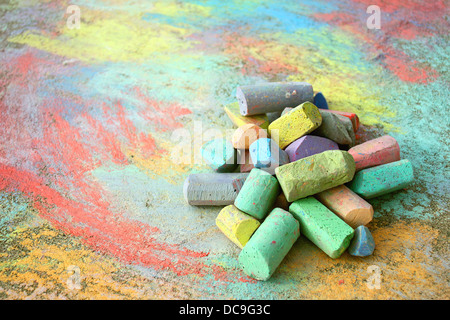 eine Sammlung von bunten Bürgersteig Kreide ist auf eine Regenbogen-Zeichnung, draußen auf dem Bürgersteig aufgetürmt. Stockfoto