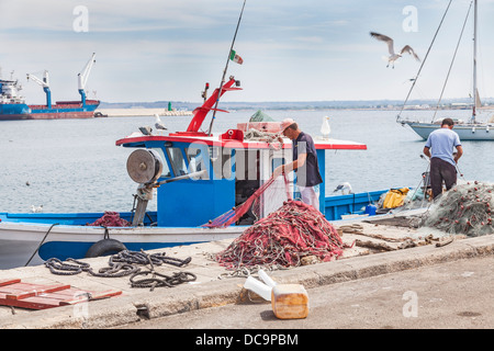 Fischer, die Pflege ihrer Fischernetze im Hafen von Galipoli, Apulien, Salento Region des südlichen Italien Stockfoto