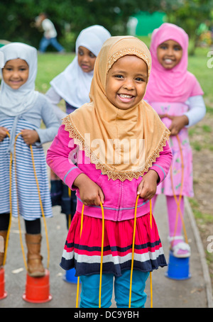 Der St.-Pauls-Kindergarten und das Kinderhaus, Bristol UK - A somalische Mädchen auf Stelzen auf dem Spielplatz spielen. Stockfoto