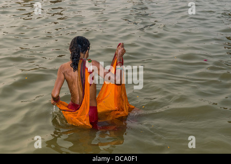 Frau trägt einen orangefarbenen Sari in Baden in der Sangam, dem Zusammenfluss der Flüsse Ganges und Yamuna Saraswati, die Stockfoto