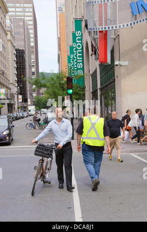 Mann schob sein Fahrrad über die Straße in der Innenstadt von Montreal, Québec, Kanada. Stockfoto