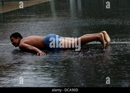 Ein junger Mann verlegen auf dem Bürgersteig In der Regen, der South Bank, London, England Stockfoto