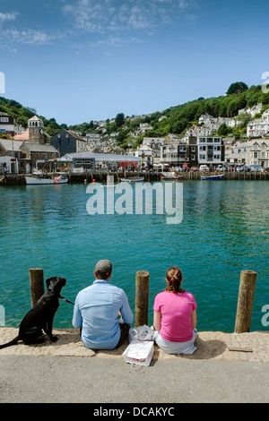 Ein Ehepaar und ihr Hund sitzt auf der Uferstraße in Looe. Stockfoto