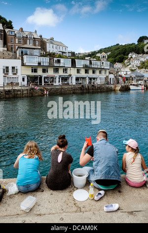 Vier junge Leute Krabben auf dem Kai in Looe, Cornwall. Stockfoto