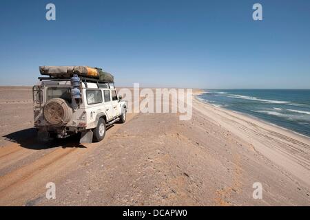 Ein Land Rover Defender reist am Strand entlang der Küste des Atlantischen Ozeans in der Nähe von Torra Bay Resort an der Skelettküste im Skeleton Coast Nationalpark, Namibia, 15. Dezember 2010. Foto: Tom Schulze Stockfoto