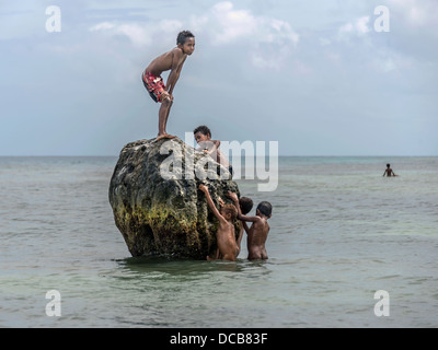 Jungs spielen auf einem großen Felsen Korallen Stockfoto