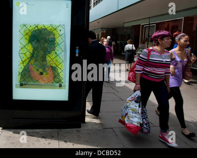 London 14.08.13: Besucher Abschnitt John Lewis Oxford Street kann man eine freie bildende Kunst-dia-Show mit freundlicher Genehmigung von der aktuellen Kunst überall-Projekt. Eine Bushaltestelle vor dem Geschäft hat eine rotierenden dia-Show von Plakaten mit so unterschiedlichen Künstlern wie Tracey Emin und Holbein der jüngere. Bildnachweis: Jeffrey Blackler/Alamy Live-Nachrichten Stockfoto