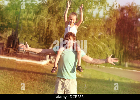 Familie Vater Mann und Sohn Junge sitzt auf Schultern spielen Outdoor Park Glück Emotion mit Sommer-Natur auf Hintergrund Stockfoto