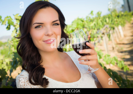 Ziemlich gemischtes Rennen junge Frau bei einem Glas Wein im Weinberg. Stockfoto