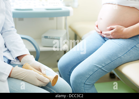 Nahaufnahme der Geburtshelfer und eine schwangere junge Frau sitzt in Klinik Stockfoto